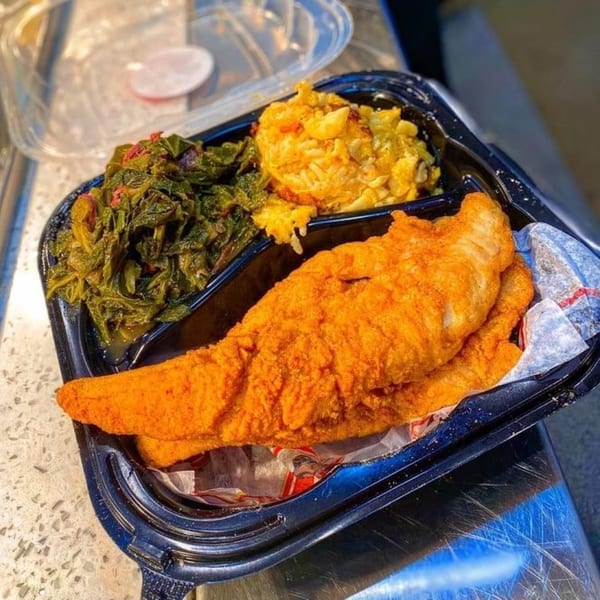 Ms. Ruby's soul food meal with fried fish, macaroni and cheese, and collard greens in a to-go container.