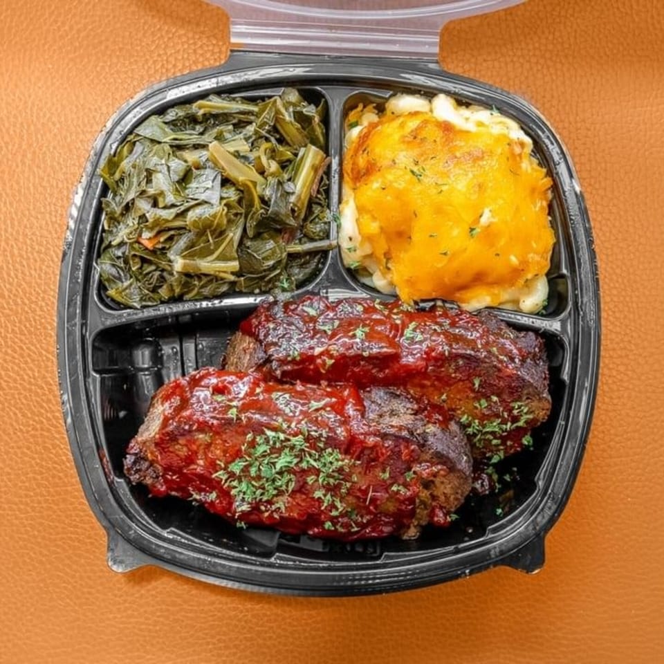 Ms. Ruby's soul food meal with meatloaf, collard greens, and macaroni and cheese in a to-go container.